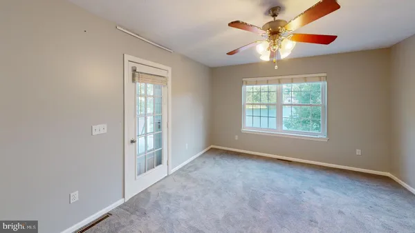 an empty room with chandelier fan and windows