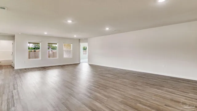 a view of an empty room with wooden floor and windows