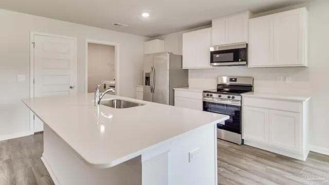 a kitchen with stainless steel appliances a microwave a sink a stove and white cabinets
