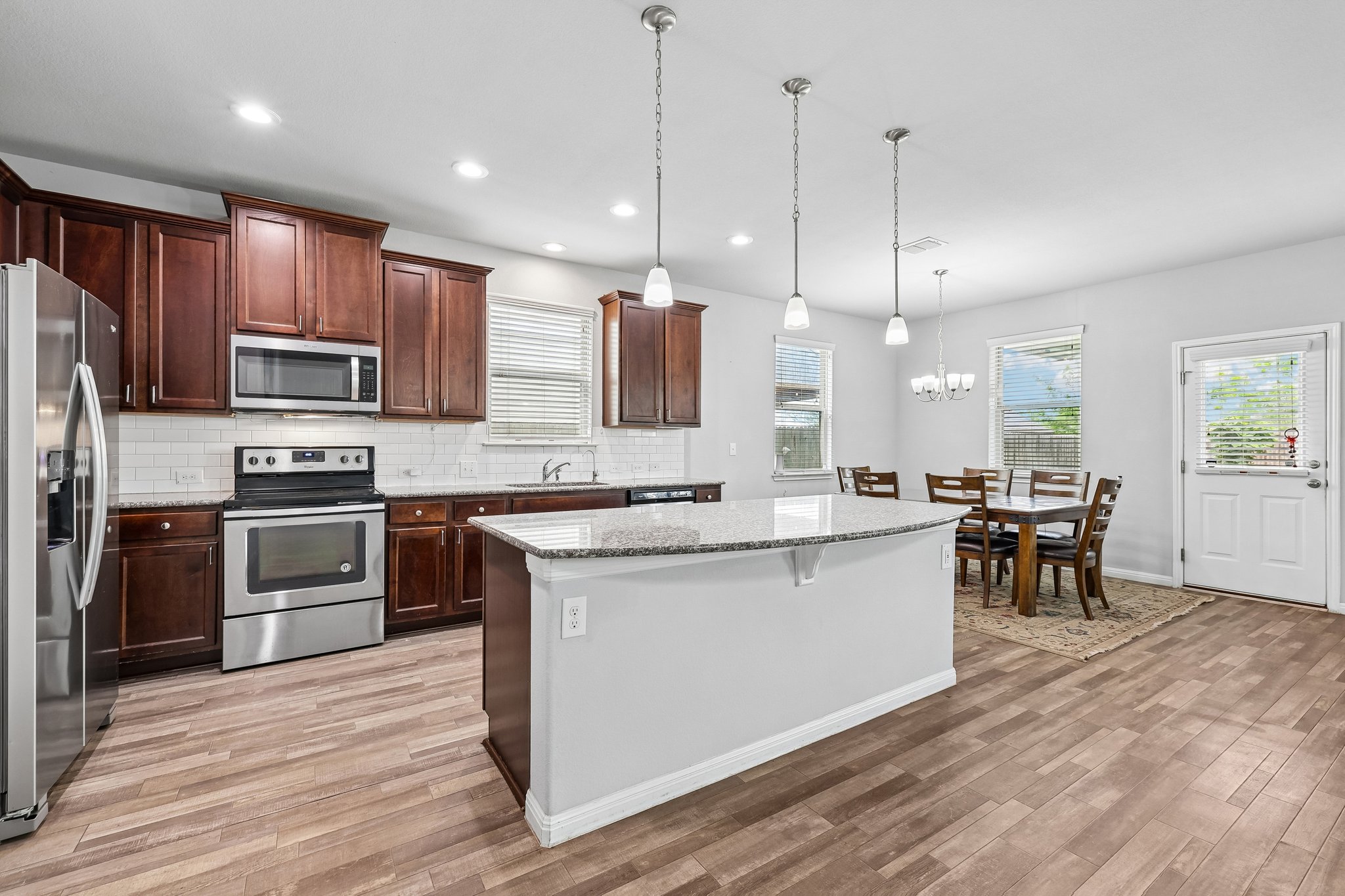 387 Guemal Road Buda, TX 78610 - Photo 9 of 39 Kitchen featuring dark wood cabinetry, stainless steel appliances, a white subway tile backsplash, and light-colored countertops