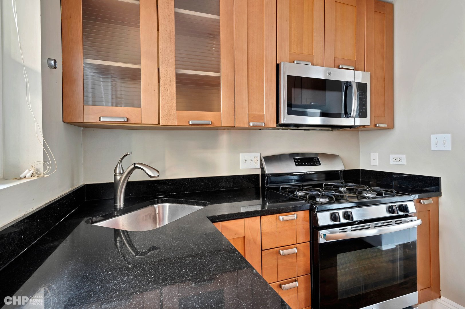 7425 North Sheridan Road, Unit 1E Chicago, IL 60626 - Photo 8 of 31 a kitchen with stainless steel appliances granite countertop a stove a microwave and a sink