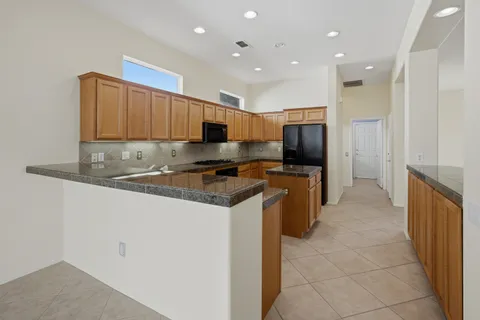 a kitchen with granite countertop a refrigerator and a stove top oven