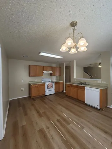 a large kitchen with stainless steel appliances granite countertop a sink dishwasher a stove and a large mirror with wooden floor