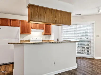 a kitchen with granite countertop wooden cabinets a sink and dishwasher