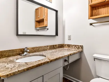 a bathroom with a granite countertop sink and a toilet
