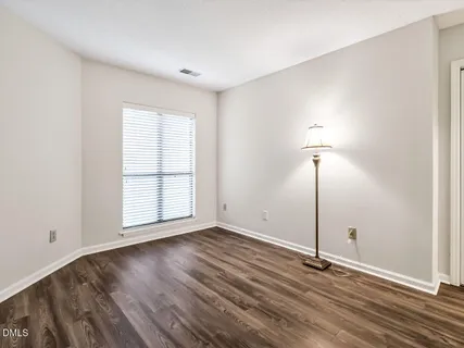 a view of an empty room with window wooden floor and a chandelier