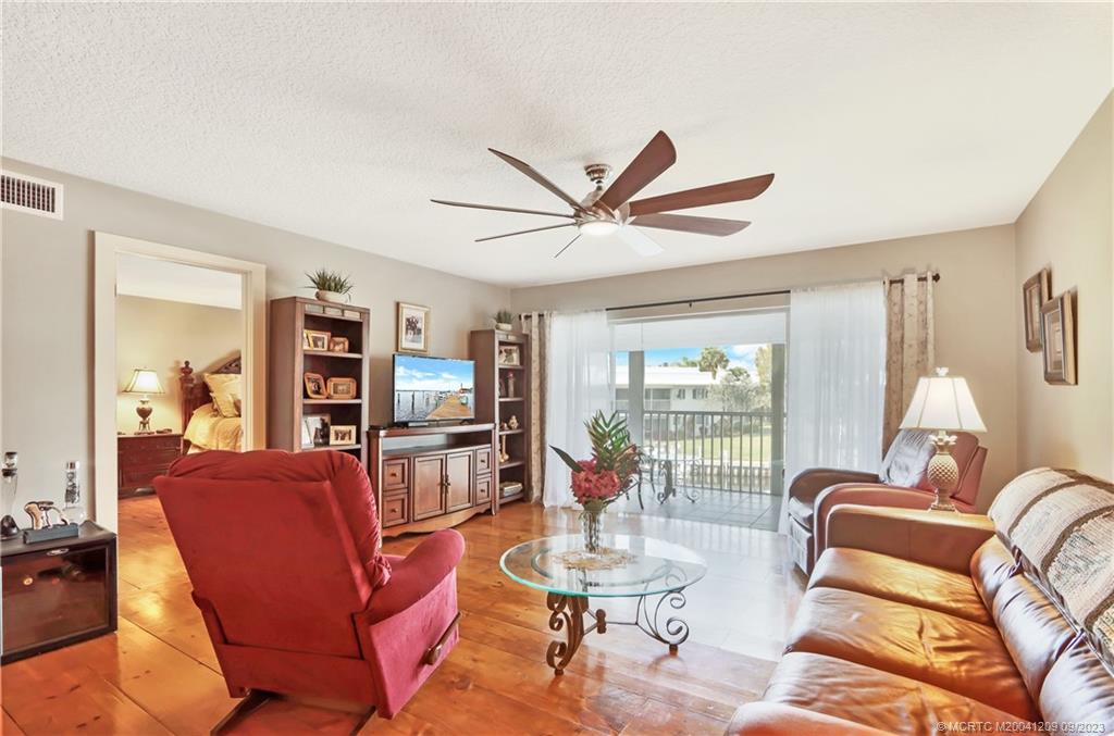 1862 Southwest Palm City Road, Unit 202 Stuart, FL 34994 - Photo 8 of 15 a living room with furniture a bookshelf and a large window