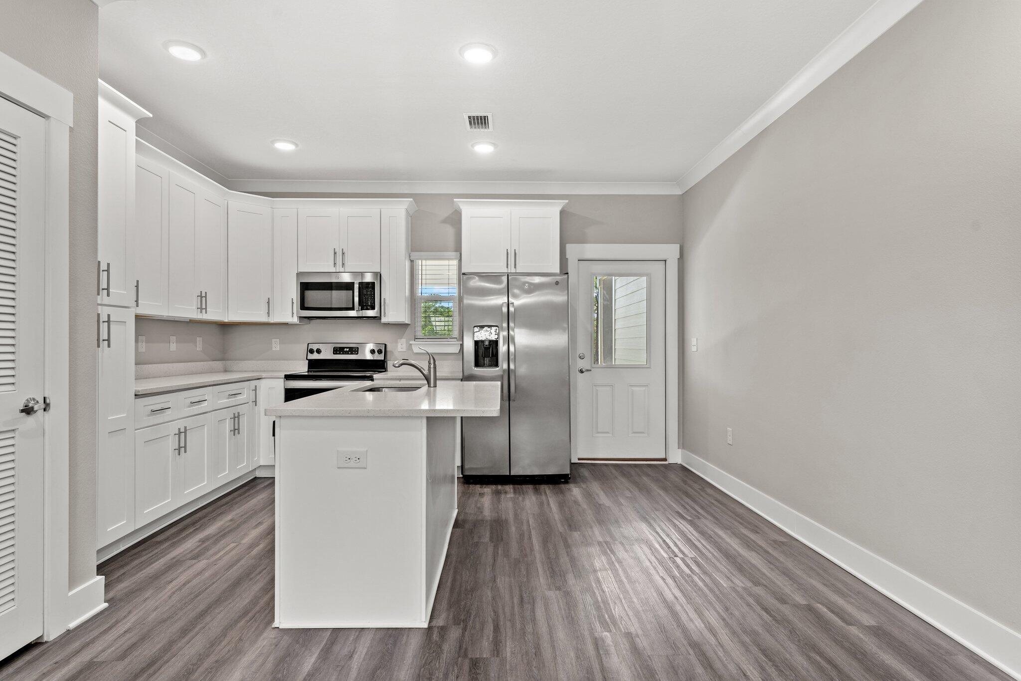 352 North Sand Palm Road, Unit VISTA Freeport, FL 32439 - Photo 8 of 29 a kitchen with wooden floors white cabinets and stainless steel appliances