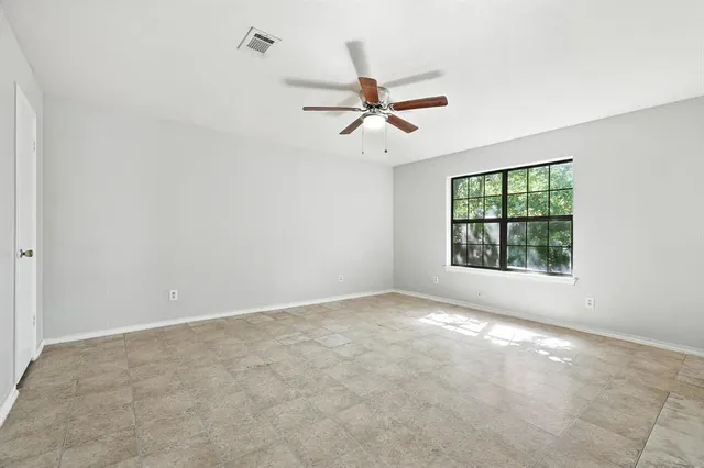 an empty room with windows and fan