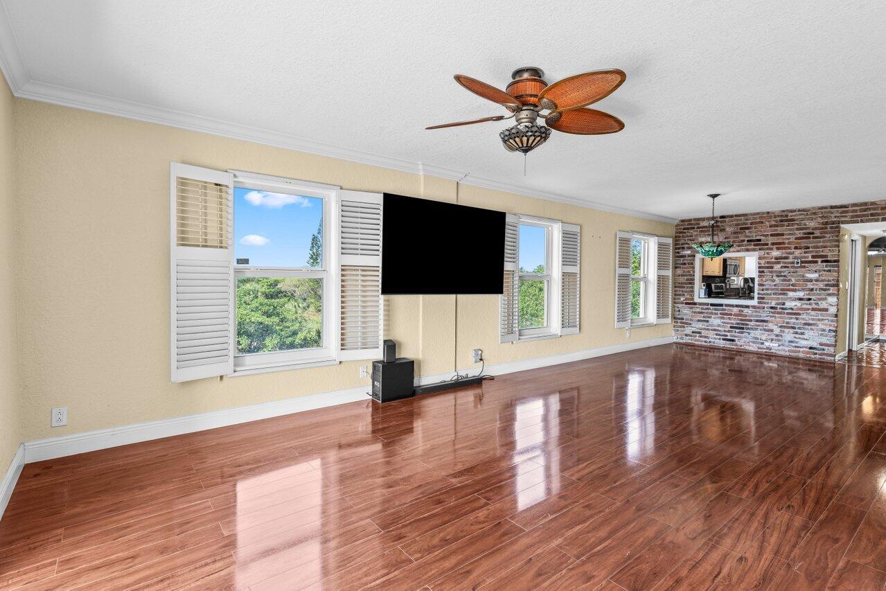 1040 Banyan Road, Unit 501C Boca Raton, FL 33432 - Photo 13 of 47 a view of a livingroom with a flat screen tv ceiling fan and hardwood floor