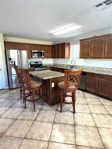 a kitchen with stainless steel appliances granite countertop a sink a stove a table and chairs