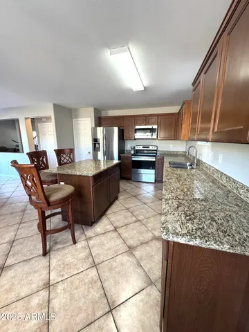 a kitchen with granite countertop a stove a sink a counter top space and cabinets
