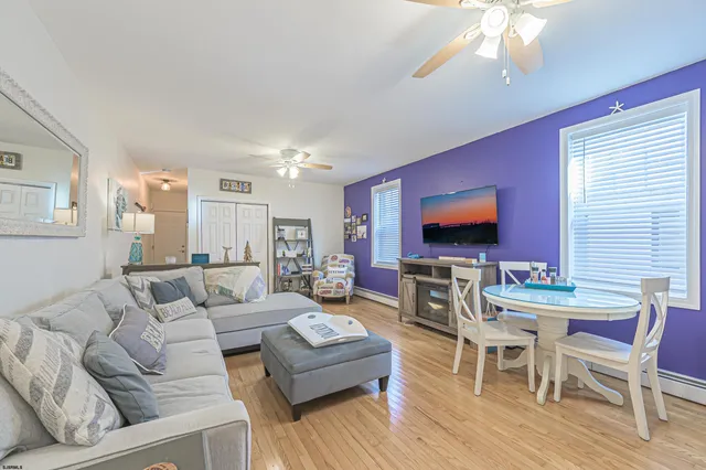 a living room with furniture a flat screen tv and a dining table