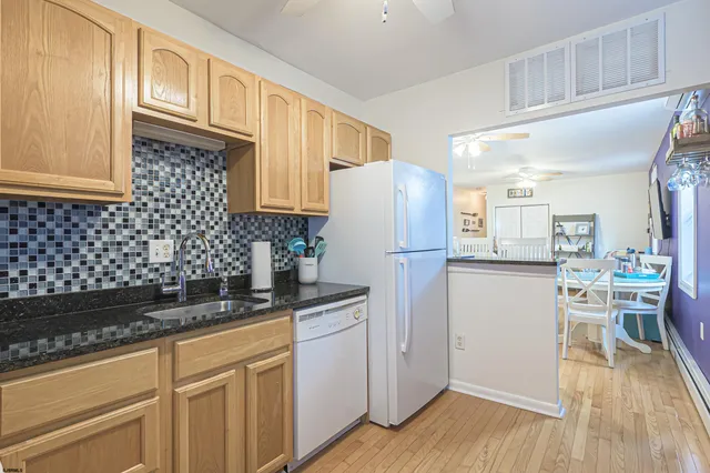 a kitchen with a refrigerator a sink and dishwasher with wooden floor