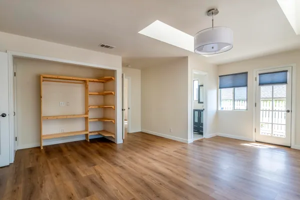 an empty room with wooden floor closet and windows