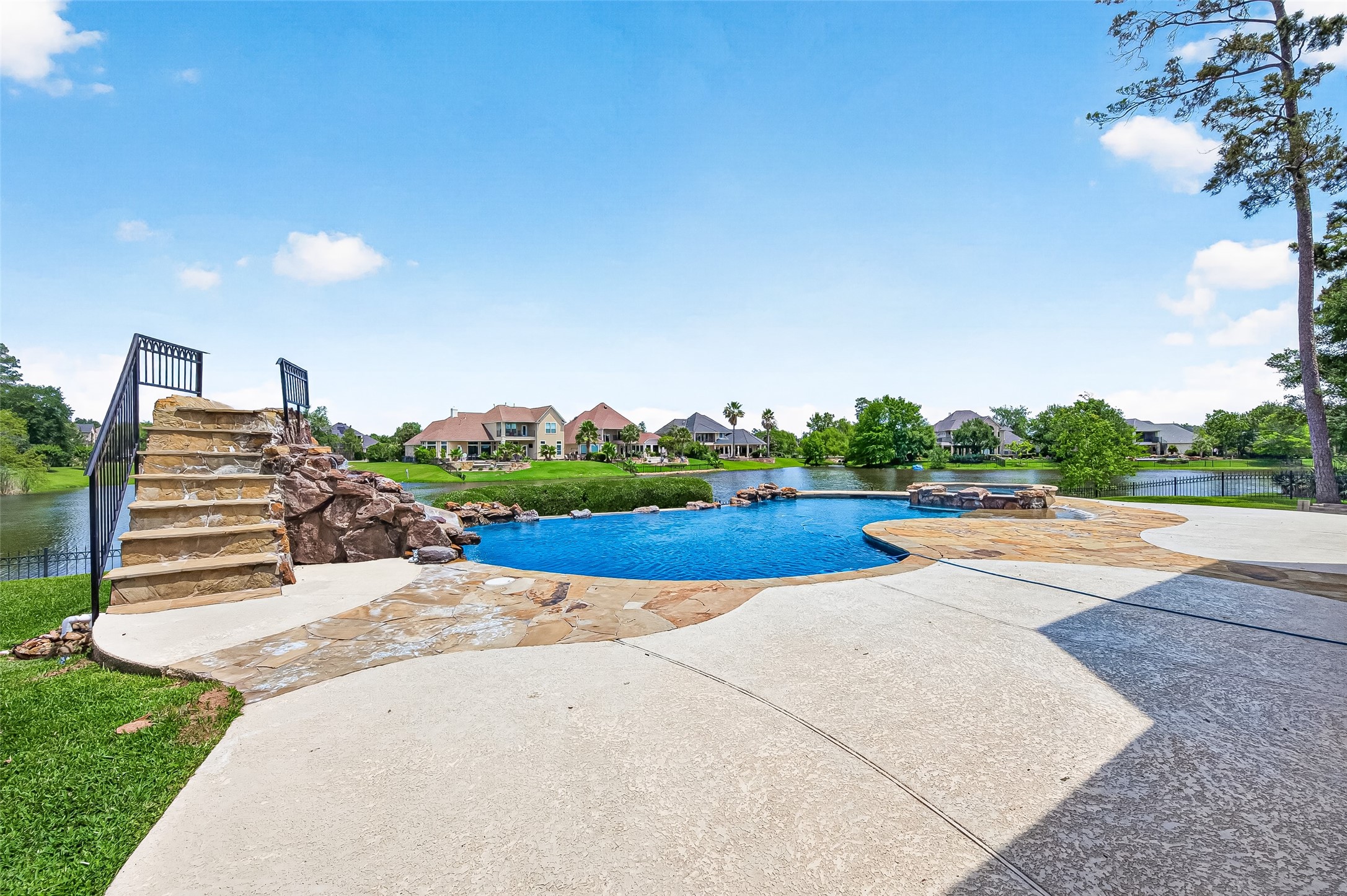 25626 Windy Isle Court Spring, TX 77389 - Photo 23 of 45 The luxurious infinity pool with a rock waterfall, slide, and hot tub overlooks a tranquil lake. What a perfect way to relax and enjoy life from your own backyard oasis. views.