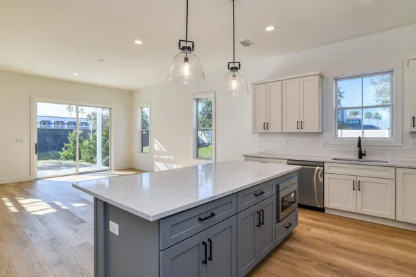 a kitchen with a stove center island a sink cabinets and a wooden floor