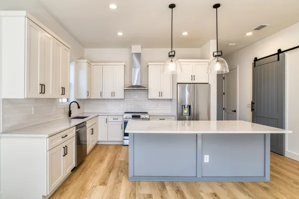 a large kitchen with stainless steel appliances granite countertop a sink a stove and a refrigerator