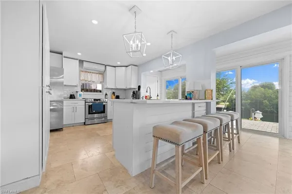 a kitchen with stainless steel appliances granite countertop a sink a stove a refrigerator a center island with a dining table and chairs