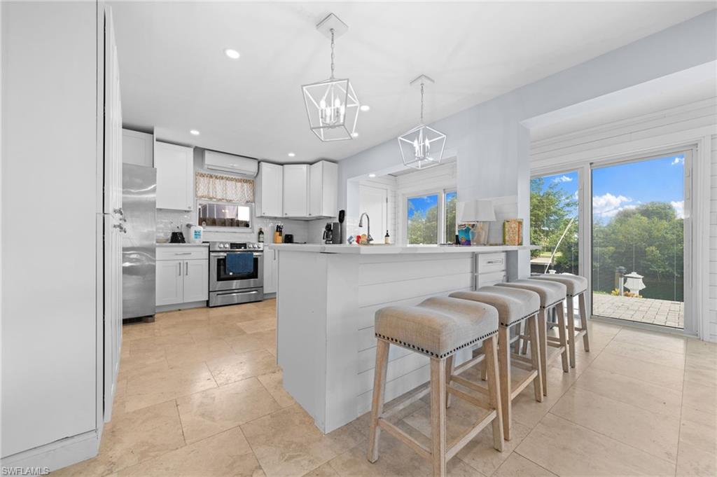 1360 Chesapeake Avenue Naples, FL 34102 - Photo 13 of 22 Kitchen featuring a kitchen island, pendant lighting, white cabinetry, appliances with stainless steel finishes, and backsplash