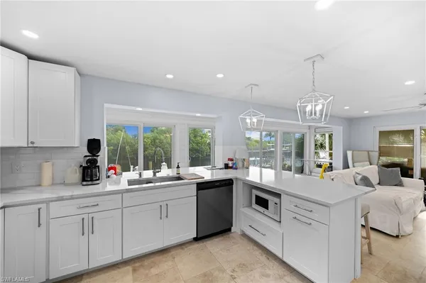 a large white kitchen with kitchen island a large window a sink and cabinets