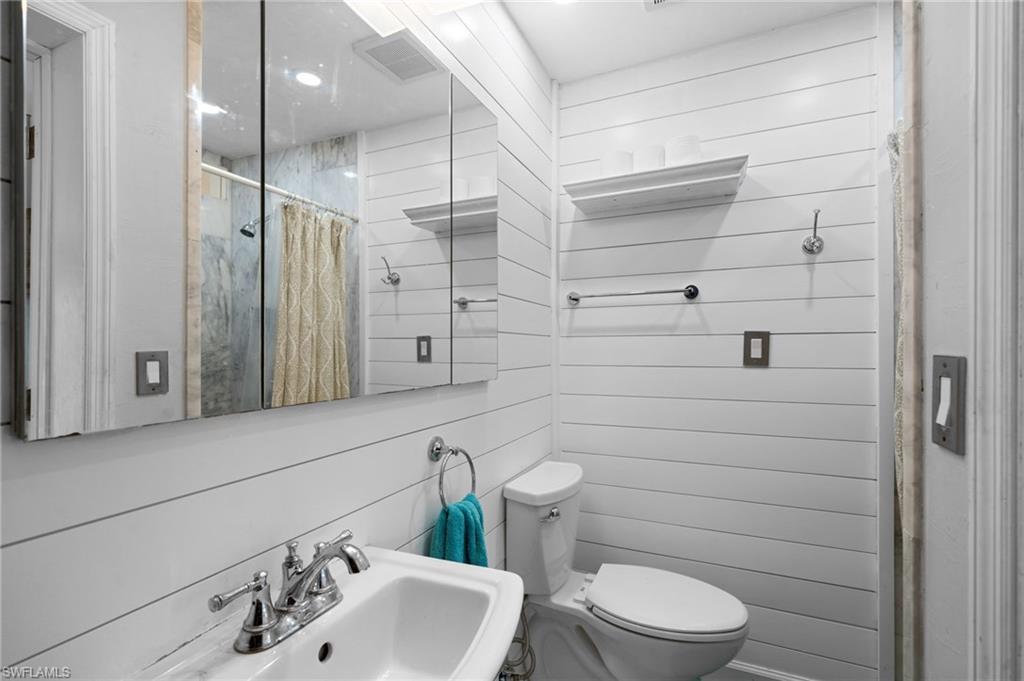 1360 Chesapeake Avenue Naples, FL 34102 - Photo 16 of 22 Bathroom featuring wood walls, sink, a shower with shower curtain, and toilet