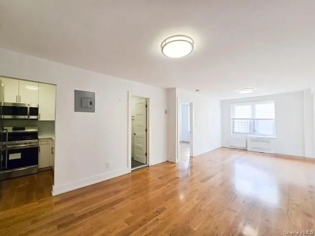 a view of a kitchen with wooden floor electronic appliances and window