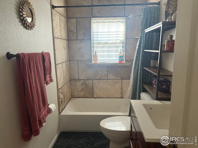 a bathroom with a tub toilet and a window