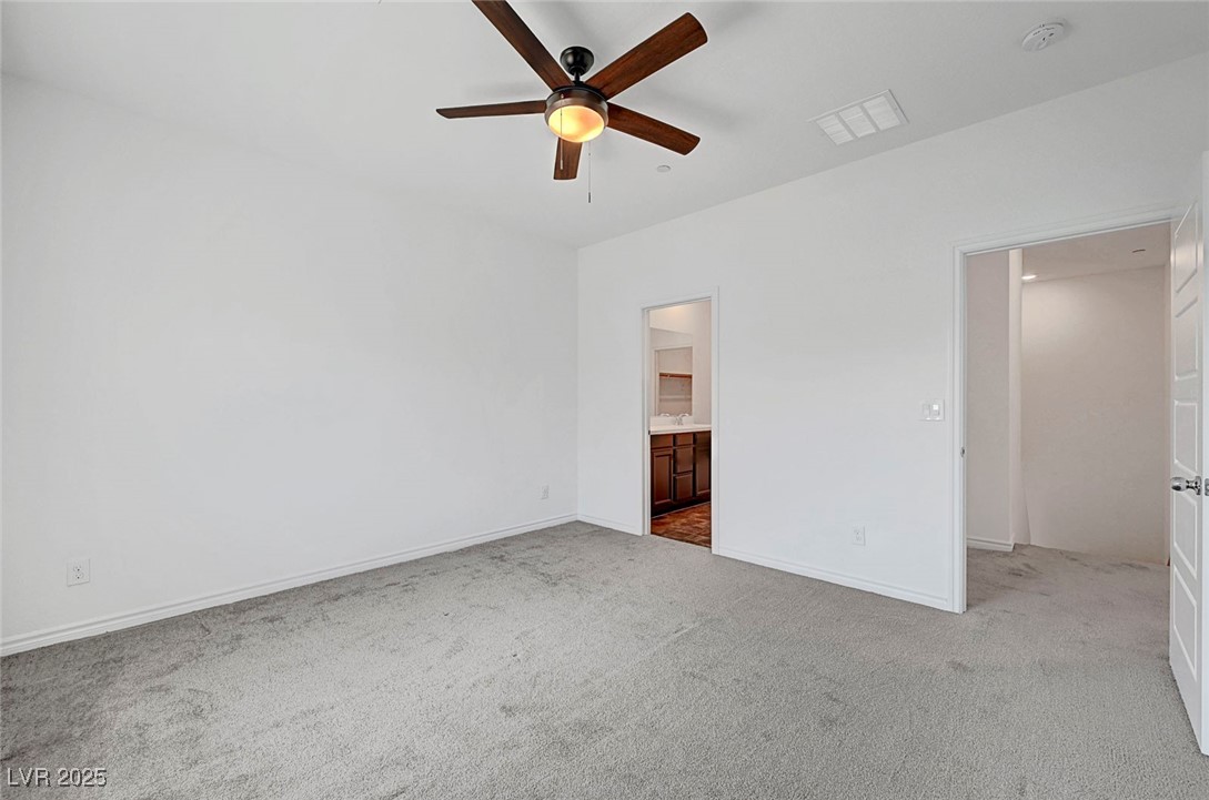 7204 North Decatur Boulevard North Las Vegas, NV 89084 - Photo 34 of 55 Unfurnished bedroom featuring carpet, baseboards, ensuite bath, visible vents, and a ceiling fan