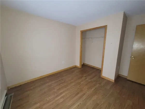 an empty room with wooden floor and closet