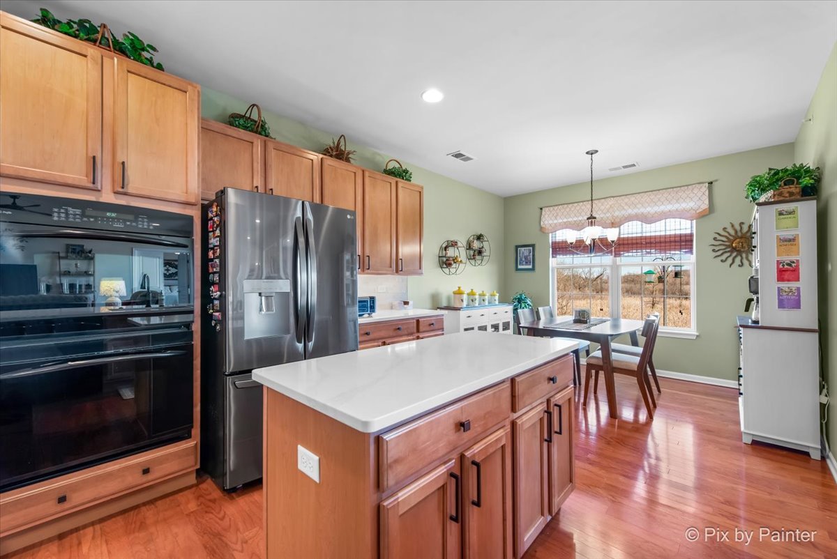 12290 Russet Lane Huntley, IL 60142 - Photo 14 of 38 a kitchen with kitchen island a stove a sink a refrigerator and chairs