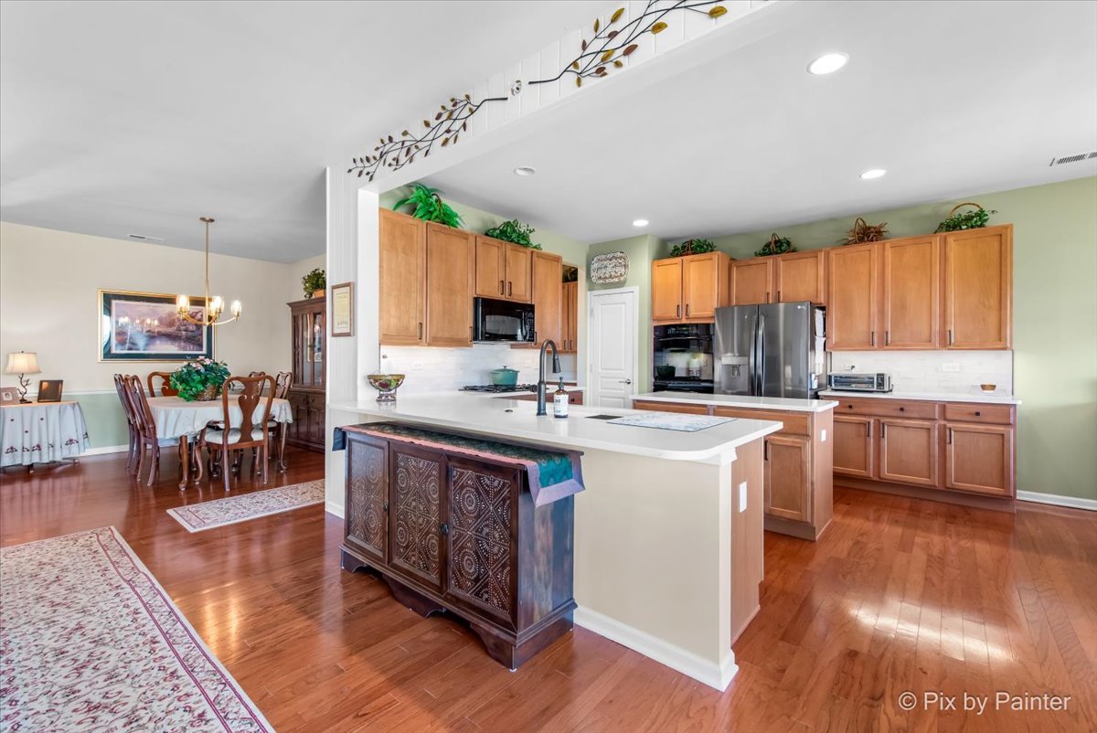 12290 Russet Lane Huntley, IL 60142 - Photo 15 of 38 a kitchen with stainless steel appliances granite countertop a stove top oven a refrigerator a sink and a dining table with wooden floor