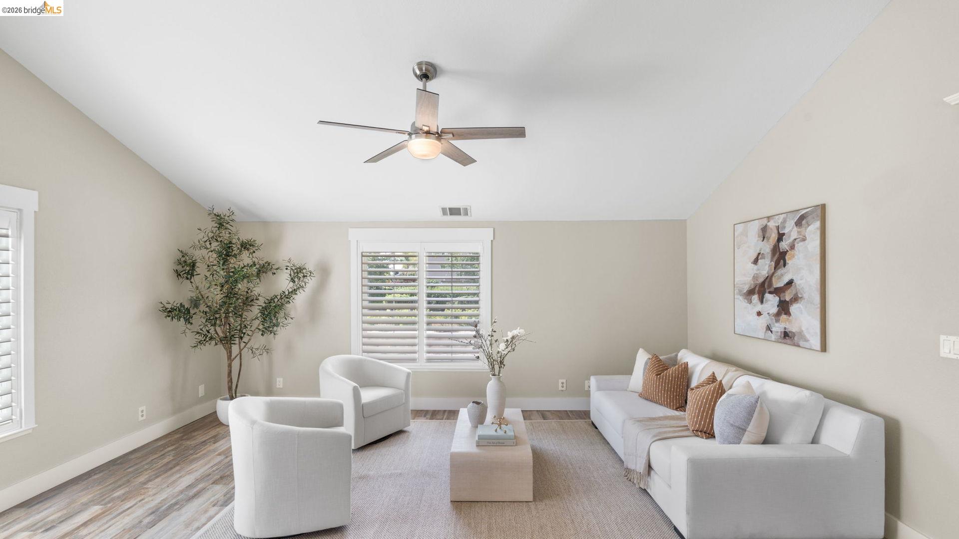 700 Brownstone Road Oakley, CA 94561 - Photo 18 of 58 Vaulted ceiling living area featuring wood-finish flooring, a contemporary ceiling fan, and multiple windows with plantation shutters