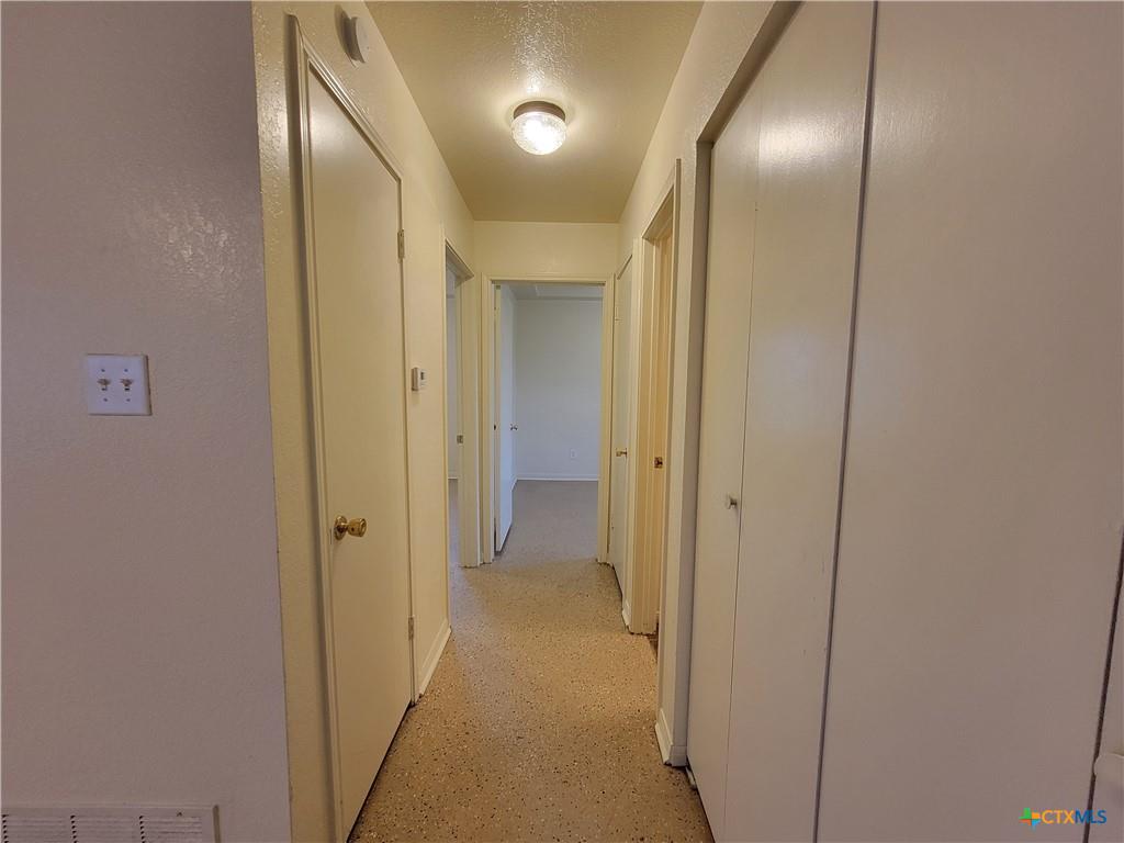 10413 Trimmier Road Killeen, TX 76542 - Photo 5 of 8 A well-lit corridor provides access to various rooms, each featuring interior doors and a neutral color palette.