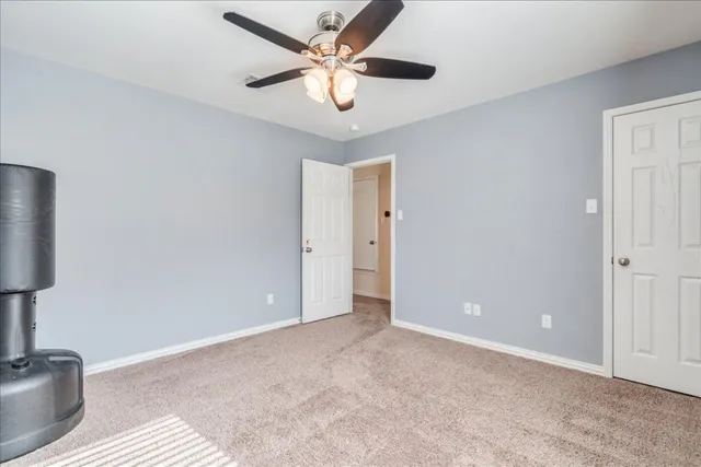 a view of an empty room with a chandelier fan