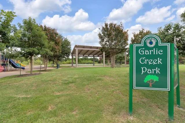 a sign of golf club on a wall under a tree