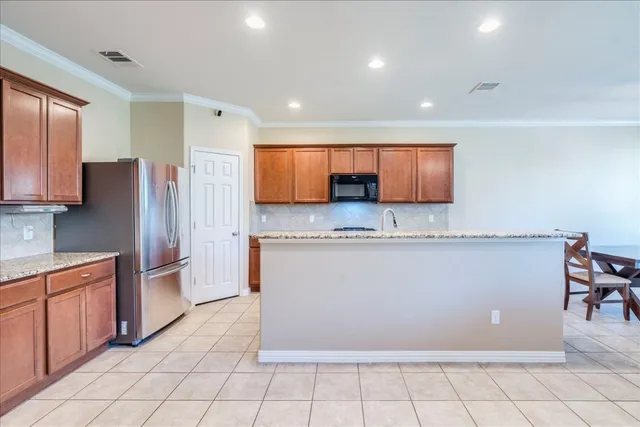 a large kitchen with stainless steel appliances granite countertop a refrigerator and a stove top oven