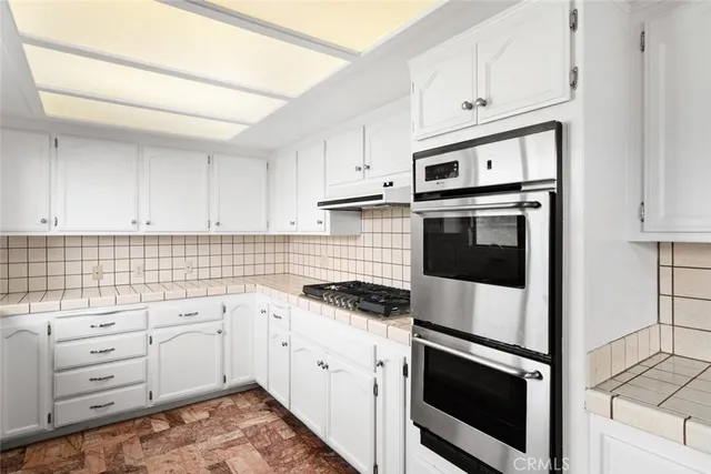 a kitchen with granite countertop white cabinets and stainless steel appliances