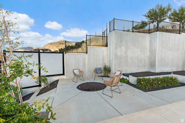 912 North Loafer Canyon Road Elk Ridge, UT 84651 - Photo 55 of 98 Outdoor patio area with concrete hardscaping, built-in fire pit, privacy fencing, and tiered landscaping