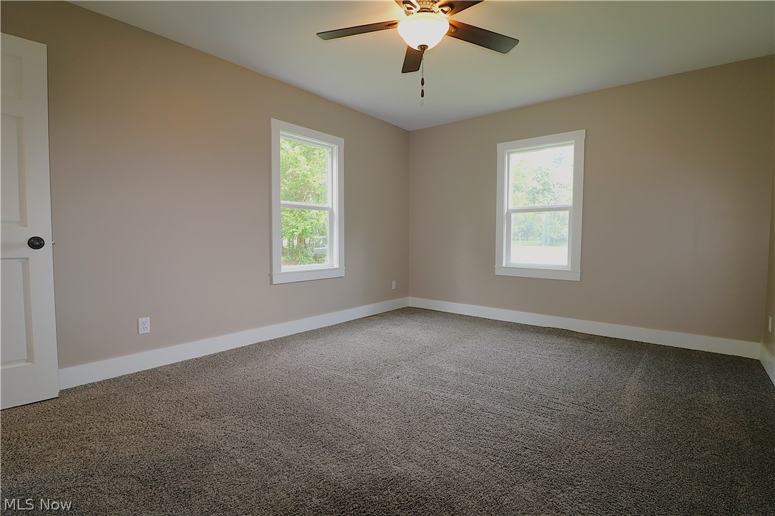 5236 Zenobia Road Wakeman, OH 44889 - Photo 9 of 31 Neutral-toned room featuring two double-hung windows, plush carpet flooring, a ceiling fan with integrated lighting, and white trim