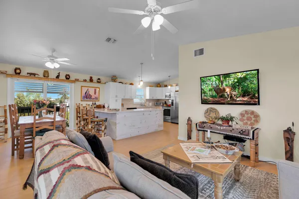 a kitchen with stainless steel appliances kitchen island granite countertop a refrigerator a stove a sink dishwasher and white cabinets with wooden floor