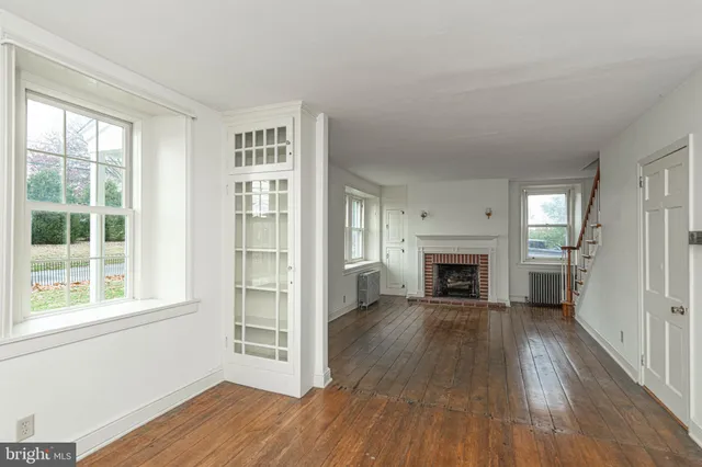 a view of a livingroom with wooden floor a fireplace and windows
