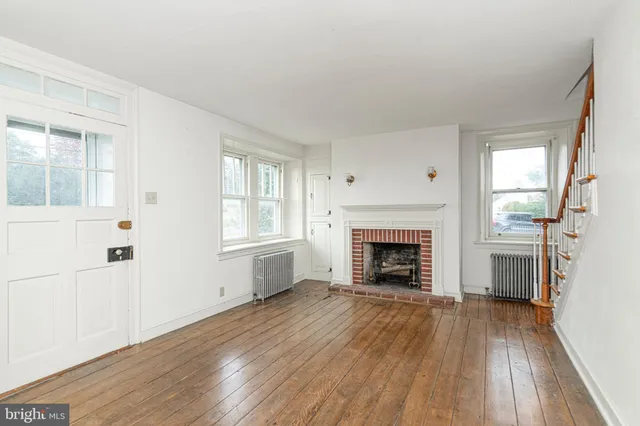 wooden floor fireplace and windows in an empty room