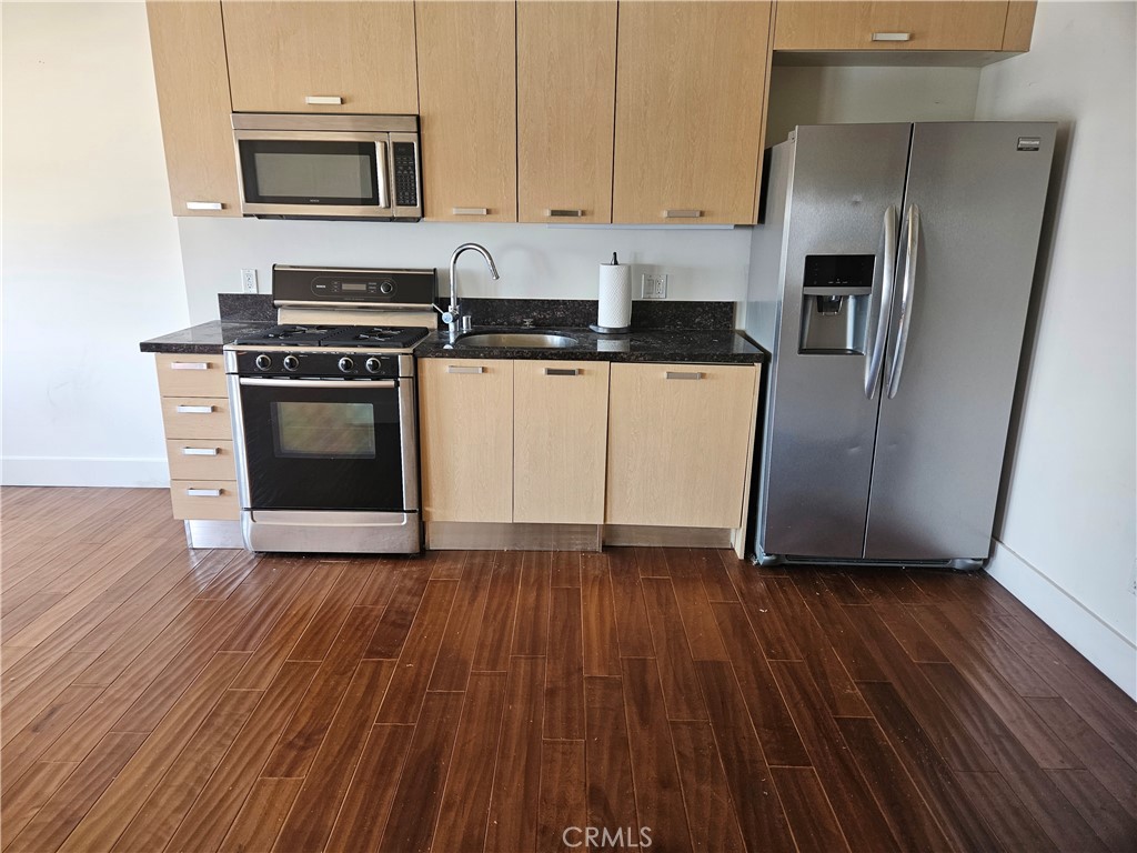 460 South Spring Street, Unit 1207 Los Angeles, CA 90013 - Photo 2 of 15 a kitchen with granite countertop wooden floors and stainless steel appliances