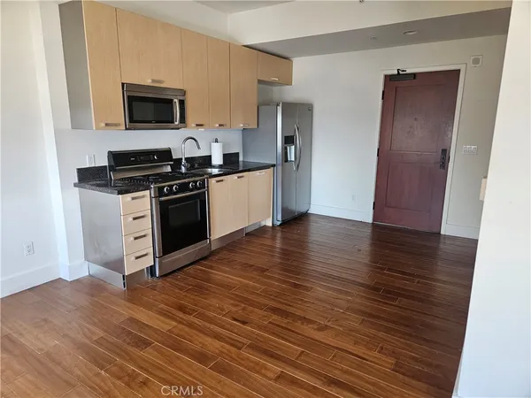 a kitchen with wooden floors and stainless steel appliances