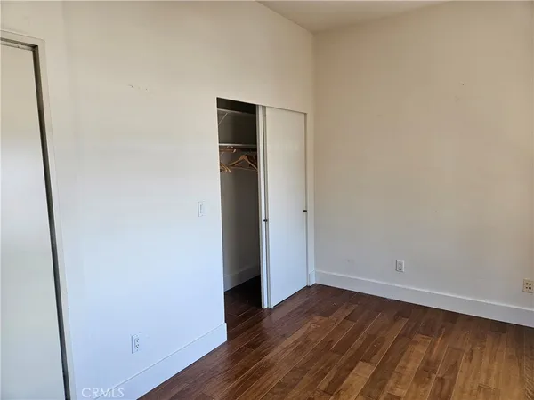 a view of an empty room with wooden floor and closet