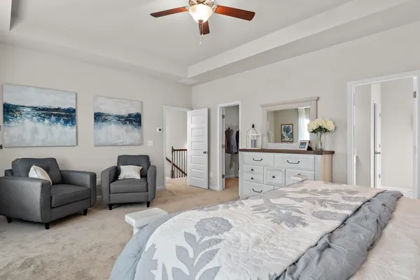 a spacious bedroom with a bed a couch and a chandelier