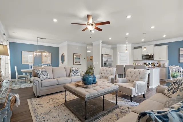 a living room with furniture kitchen view and a chandelier