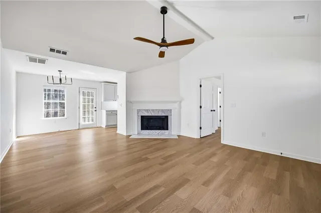 a view of an empty room with wooden floor fireplace and a window