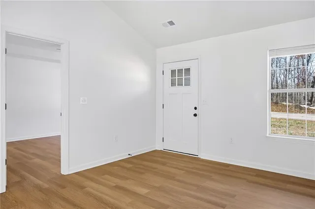 a view of an empty room with wooden floor and a window